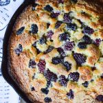 Permalink to: Blackberry Skillet Cake Overhead view of a skillet cake studded with blackberries baked and golden and ready to serve