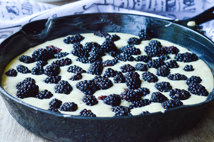 Buttermilk Cake Batter in a cast iron skillet sprinkled with fresh plump blackberries ready for baking