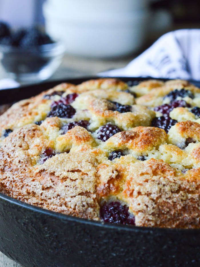 Close up view of a baked blackberry skillet cake to show the rise is about an inch over the lip of a standard 11 inch cast iron skillet