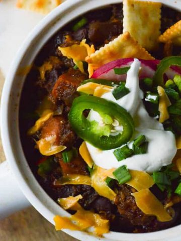 Sweet Potato Black Bean Chili with sour cream and diced jalapenos, cheese and little saltine crackers