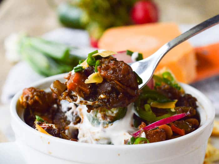 A spoonful of sweet potato and black bean chili with sour cream and green onions