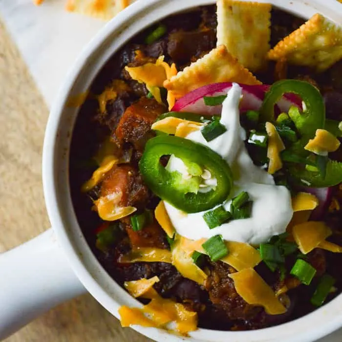 Sweet Potato Black Bean Chili with sour cream and diced jalapenos, cheese and little saltine crackers