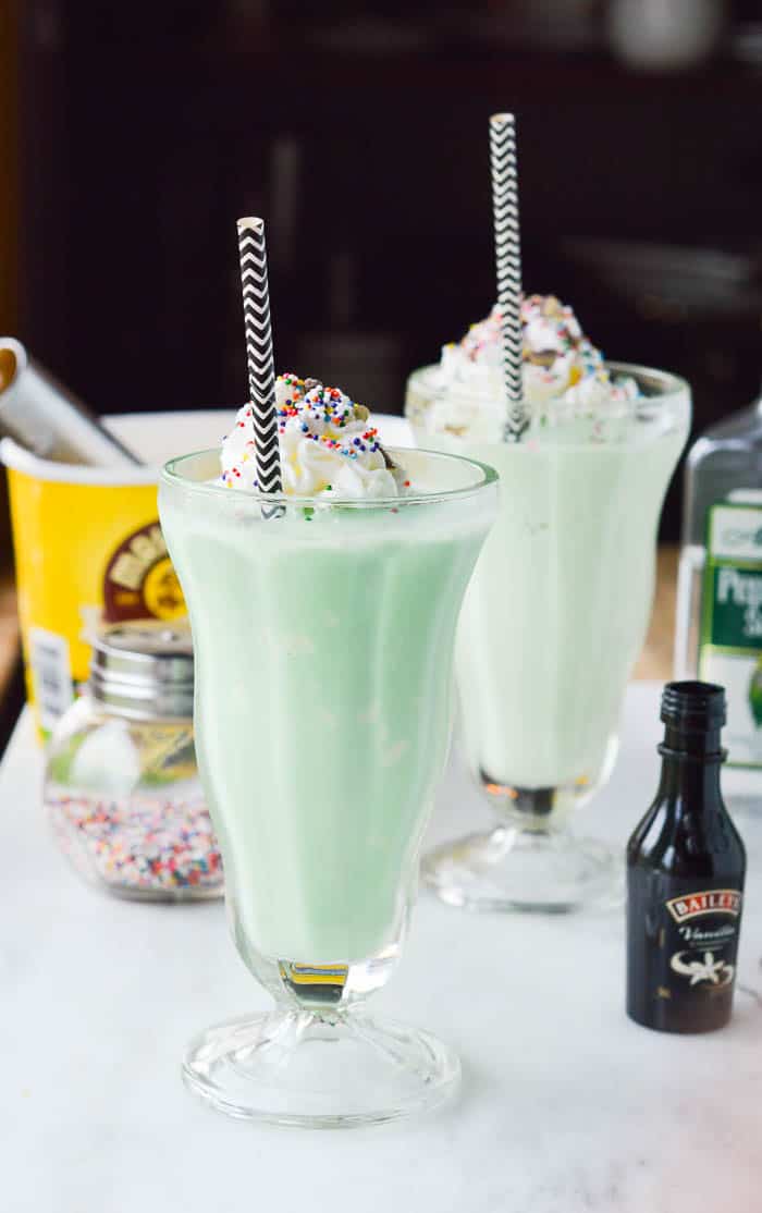 Shamrock Schnapps Shakes are minty green and perfect for St. Patrick's Day! So pretty with whipped cream and rainbow sprinkles. 