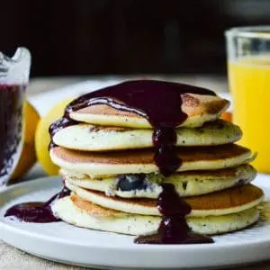 A stack of Lemon Ricotta Pancakes topped with warm blueberry syrup.