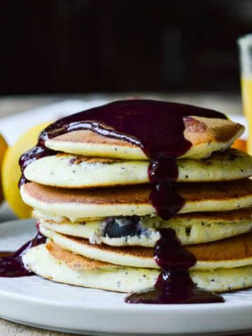 A stack of Lemon Ricotta Pancakes topped with warm blueberry syrup.
