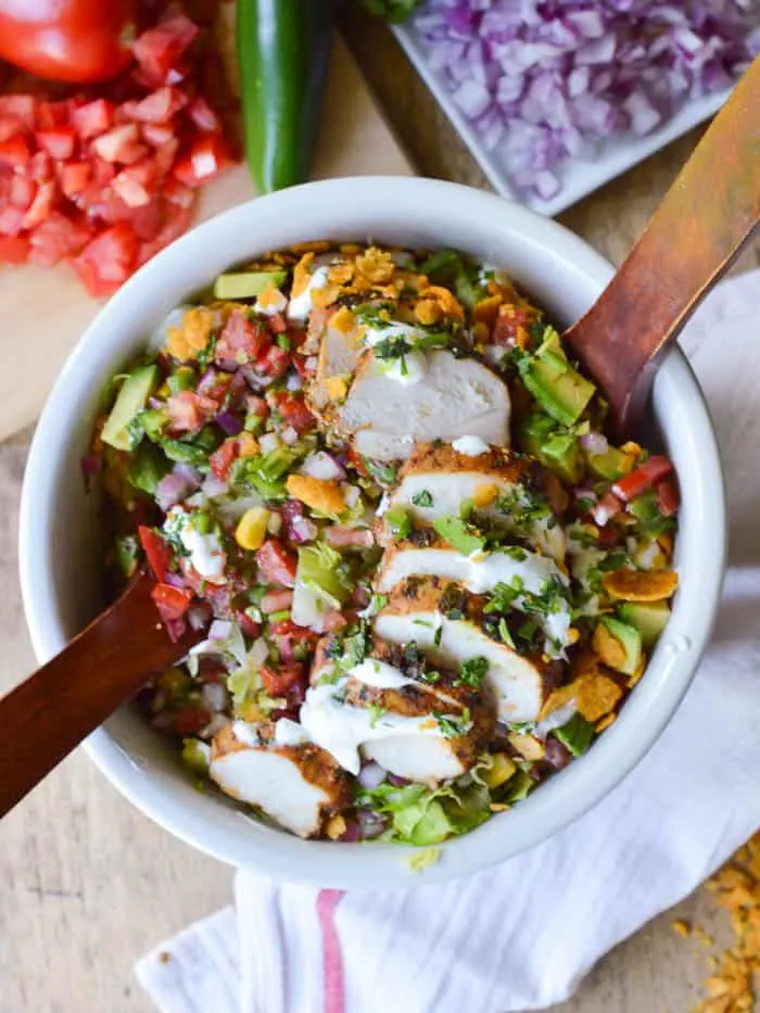 overhead view of a big bowl of southwestern chicken salad with wooden salad tongs