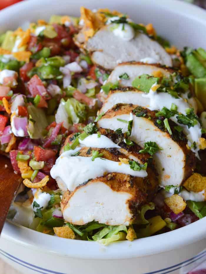 Southwestern Chicken Salad is loaded up with sliced cilantro chicken, fresh pico de gallo. cheese, and crushed corn chips