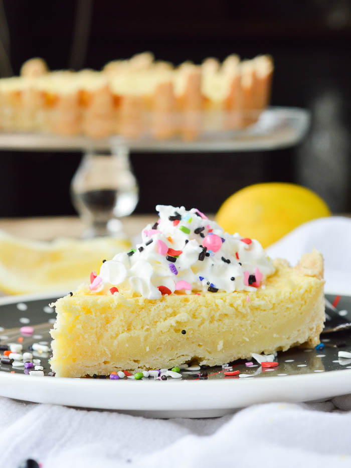 A simple slice of Irish Lemon Pudding Tart topped with whipped cream and sprinkles.