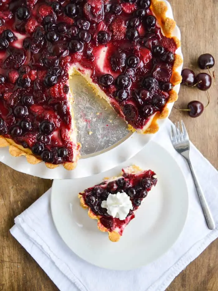 A cream cheese pie topped with cherries and berries with a polenta-based crust