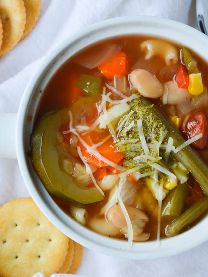 Summer Vegetable Soup with a dollop of pesto on top is colorful and loaded with garden veggies