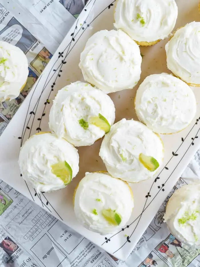 A plate of tequila cupcakes covered in whipped margarita buttercream and wedges of lime