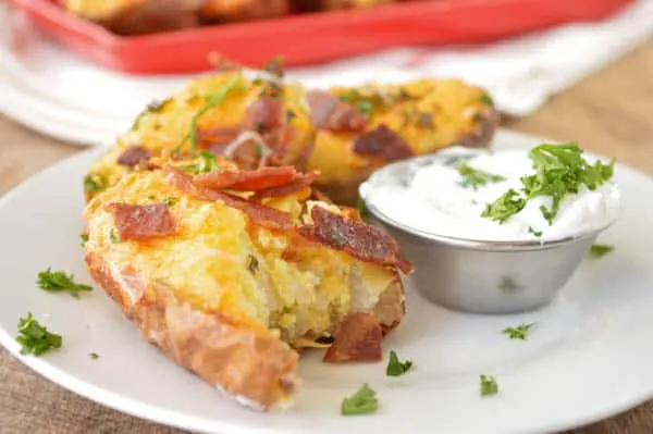 Twice Baked Breakfast Potatoes served with sour cream with a nice big bite taken, so you can see the fluffy egg and potatoes inside
