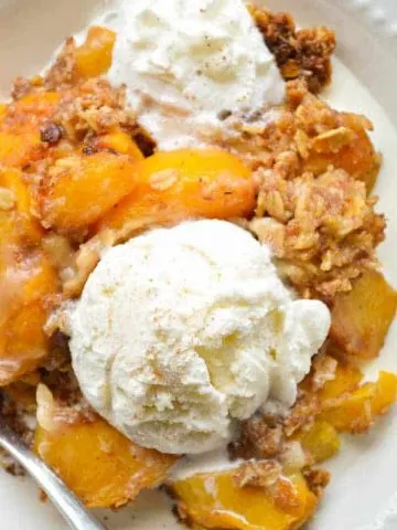 Warm fresh peaches are slow cooked with a tasty oatmeal topping and spiced rum, and then topped with vanilla ice cream!