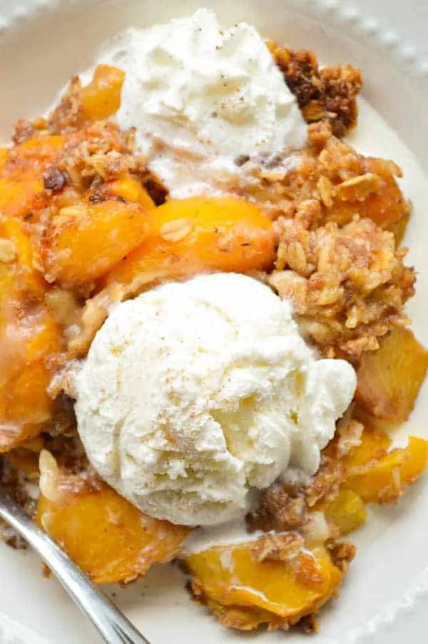 Warm fresh peaches are slow cooked with a tasty oatmeal topping and spiced rum, and then topped with vanilla ice cream!