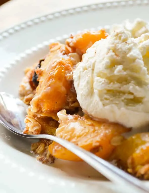 Fresh peaches are slow cooked with rum, spices, and a crumbly oatmeal topping to make this boozy peach cobbler.