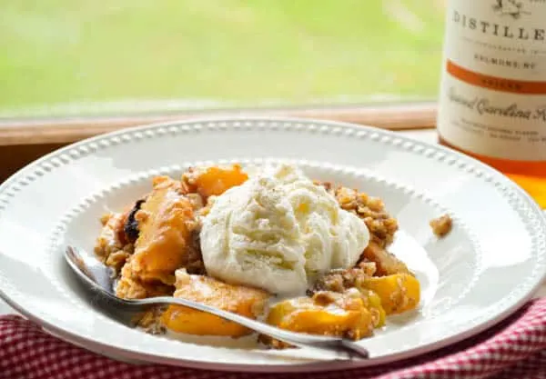 Slow cooker boozy peach cobbler with ice cream is such a delicious way to celebrate summer!