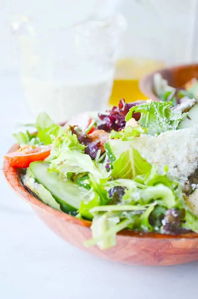 A bowl loaded with bright green lettuce, croutons, and other Italian salad veggies, coated in the best creamy Italian dressing