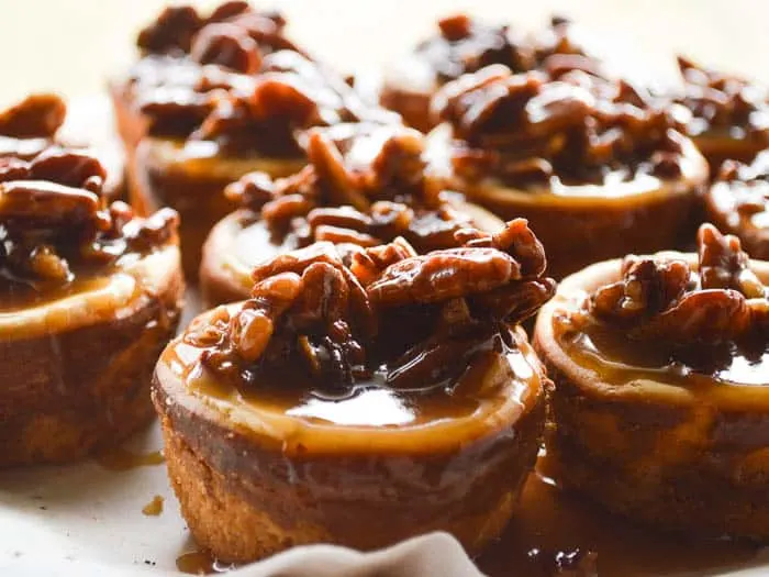 Little simple cheesecakes doused in homemade spiced rum caramel studded with pecans. Spiced Rum Pecan Cheesecakes are 4-5 bites each and decadent!