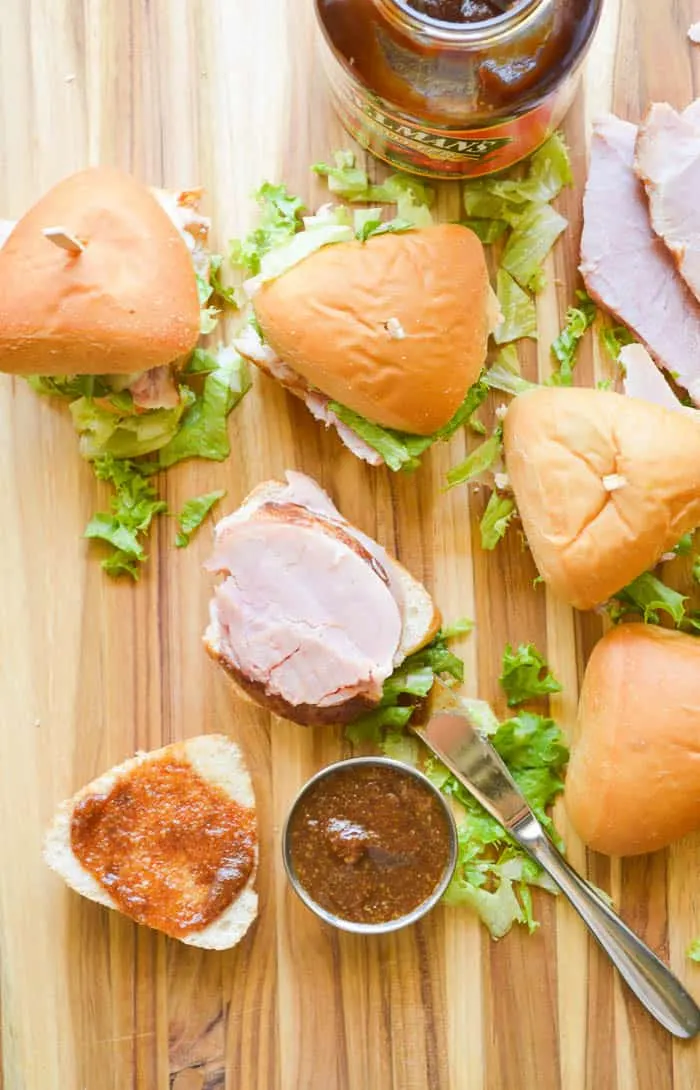 Apple Butter Glazed Ham Sandwiches on a cutting board with additional apple butter glaze to top 