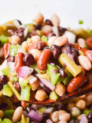 The Best Easy Bean Salad Recipe image of brightly colored bean salad on a wooden spoon