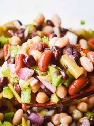 The Best Easy Bean Salad Recipe image of brightly colored bean salad on a wooden spoon