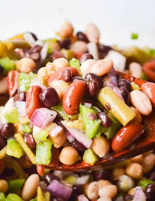 The Best Easy Bean Salad Recipe image of brightly colored bean salad on a wooden spoon