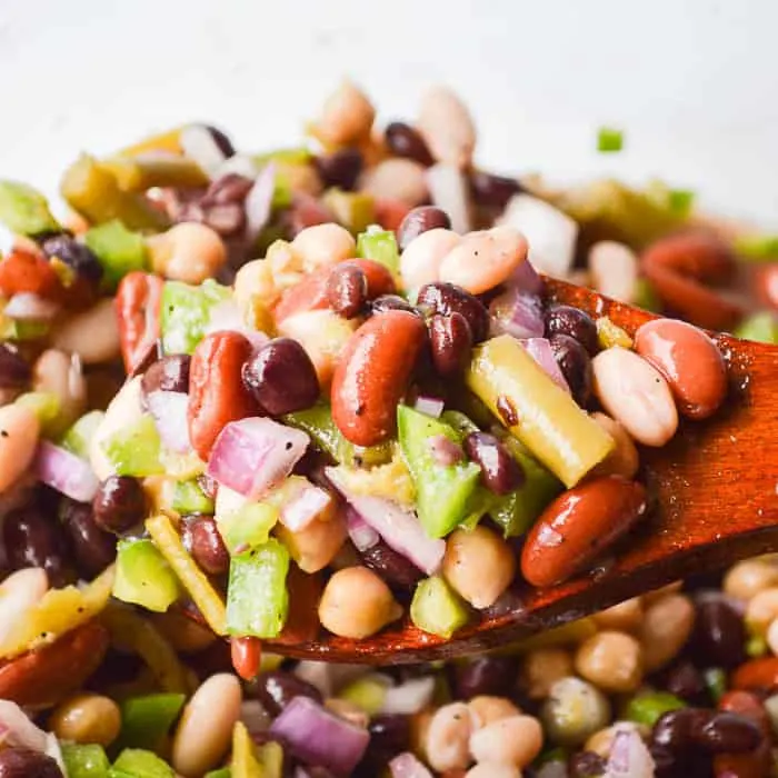 The Best Easy Bean Salad Recipe image of brightly colored bean salad on a wooden spoon