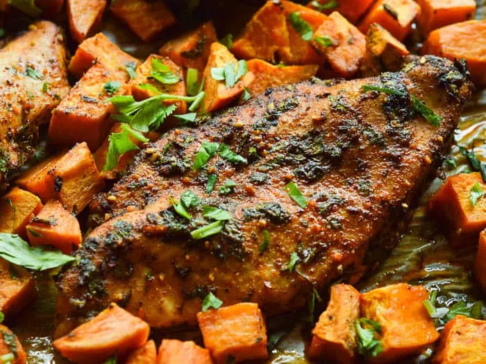 Close up landscape shot of tender and juicy Sheet Pan Roasted Chili Chicken and diced roasted sweet potatoes