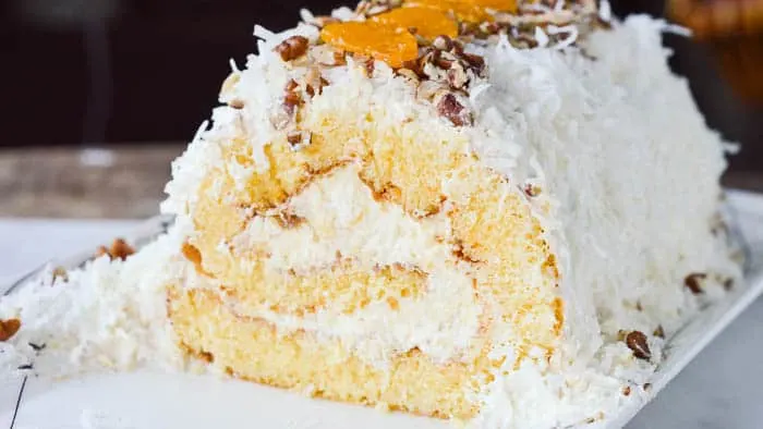 Yellow sponge cake rolled and filled with pineapple fluff, mandarin oranges, and topped with coconut and pecans.