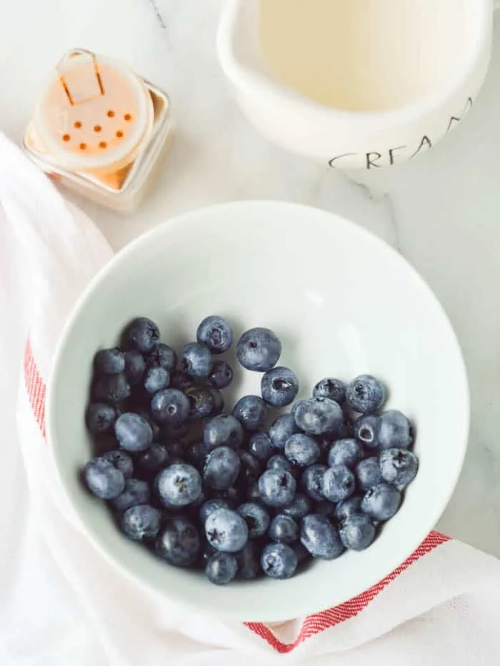 Bowl of fresh blueberries, decanter of milk, and a glass jar of cinnamon; the ingredients you need to make blueberry cinnamon oatmeal