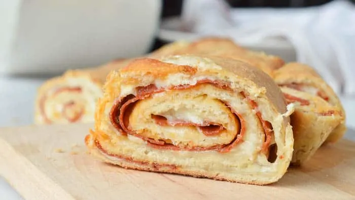 A slice of easy stromboli recipe layered with meats and cheeses wrapped and rolled in a soft dough that's baked to golden perfection