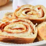 Permalink to: Easy Stromboli Recipe Slices of Easy Stromboli in a white dish with a red and white flour sack towel ready for serving