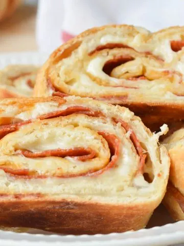 Slices of Easy Stromboli in a white dish with a red and white flour sack towel ready for serving