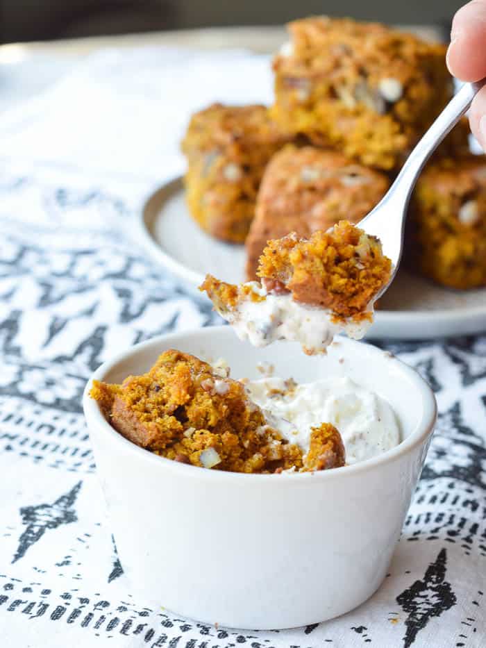 A bite of warm Pumpkin Cake Bar on a fork with melty vanilla bean ice cream