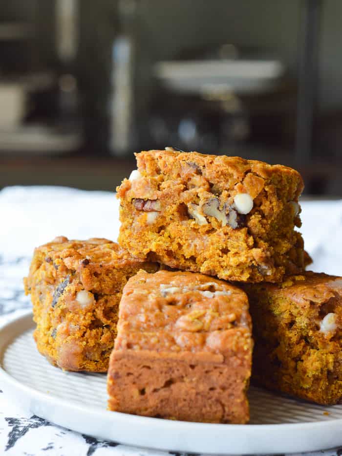 A stack of Pumpkin Cake Bars studded with white chocolate chips and chopped pecans. These bars are simple to make, super moist, and can be eaten like a bar cookie or with a fork!