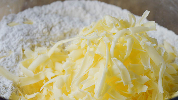 a half cup of grated butter in a bowl of flour ready to be cut together into coarse crumbles for making perfect scones