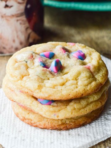 Unicorn Cake Mix Cookies stacked on a napkin next to a cup of coffee ready to eat