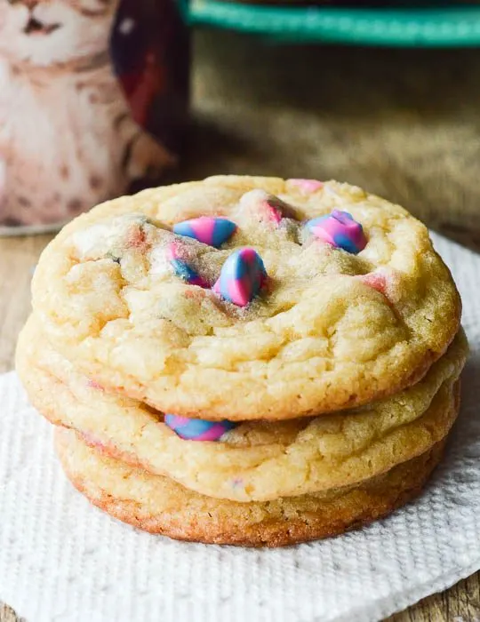 Unicorn Cake Mix Cookies stacked on a napkin next to a cup of coffee ready to eat