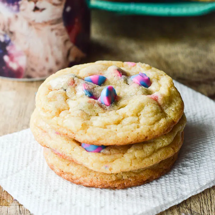 Unicorn Cake Mix Cookies stacked on a napkin next to a cup of coffee ready to eat