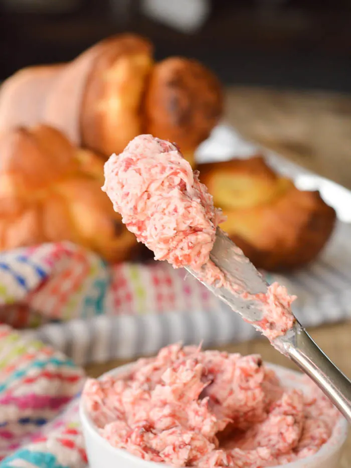 A dollop of whipped and creamy strawberry butter on the end of a small butter knife ready for spreading.