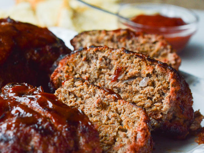 Close up slices of the best grilled meatloaf topped with spicy ketchup