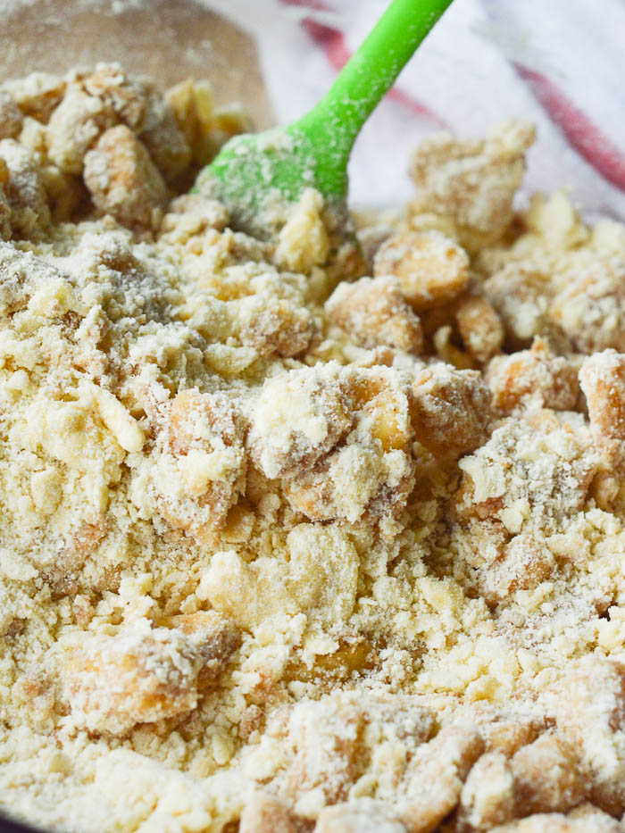 A close up of fresh apple pie filling folded into the butter and flour mixture of the scone batter so that you can see the chunky and slightly dry texture before adding the milk. 