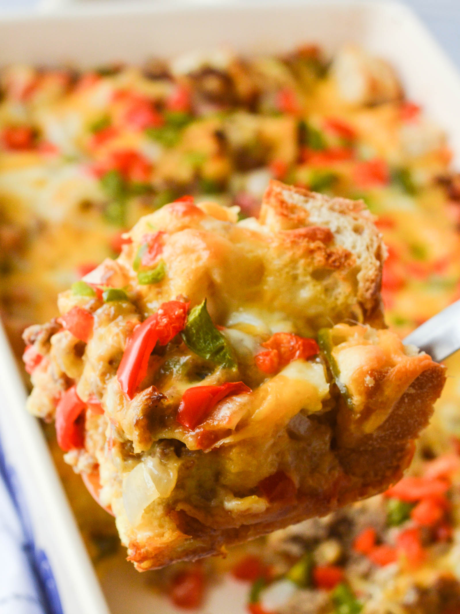 A hearty slice of Breakfast Strata with Sausage, dotted with red and green bell peppers and melted cheese. 
