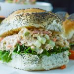 Buffalo Chicken Salad piled onto a fluffy poppy seed roll with leafy lettuce.