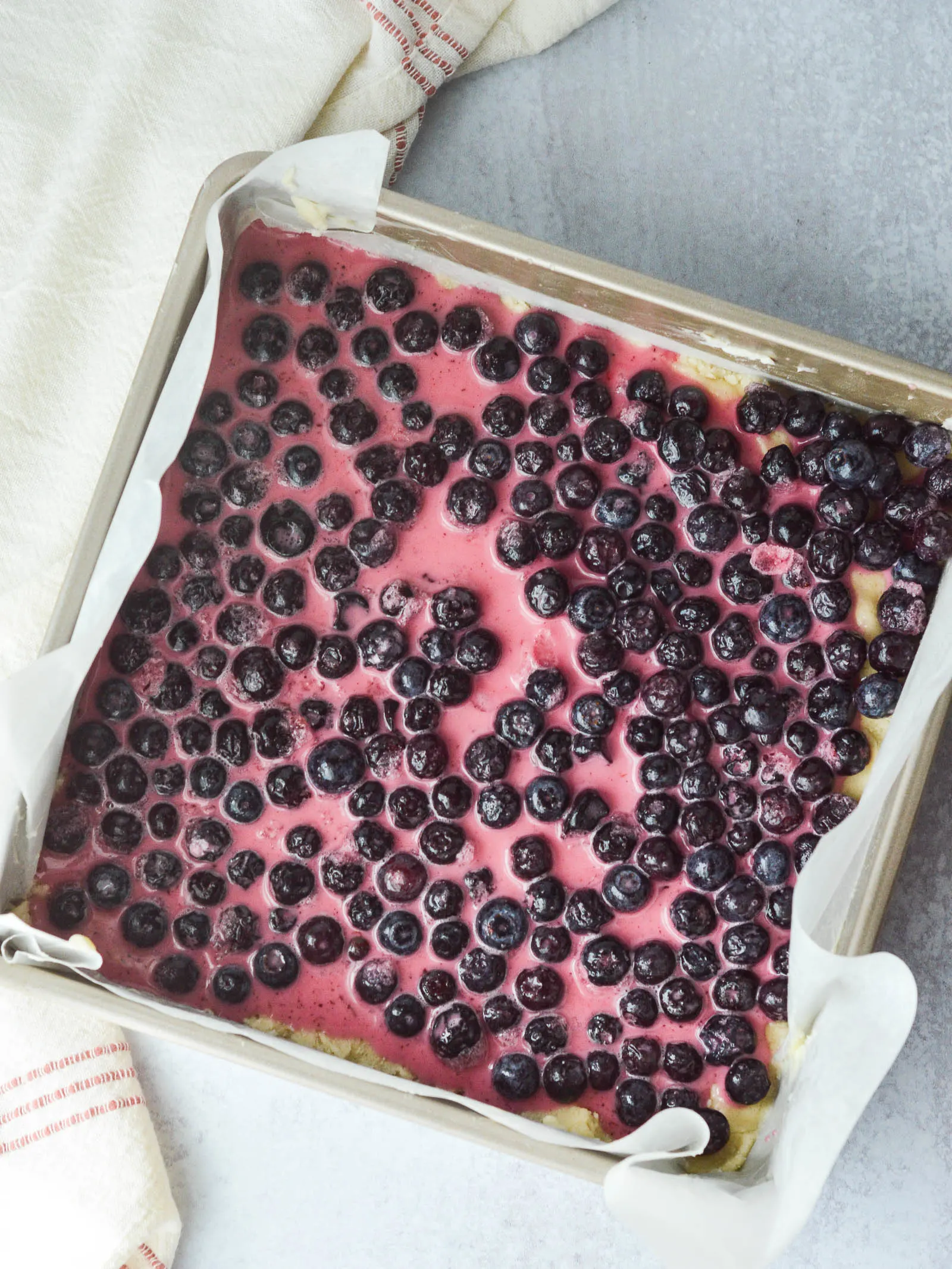 Overhead view of blueberries that have been tossed in champagne, cornstarch, and sugar, and then poured over a shortbread crust