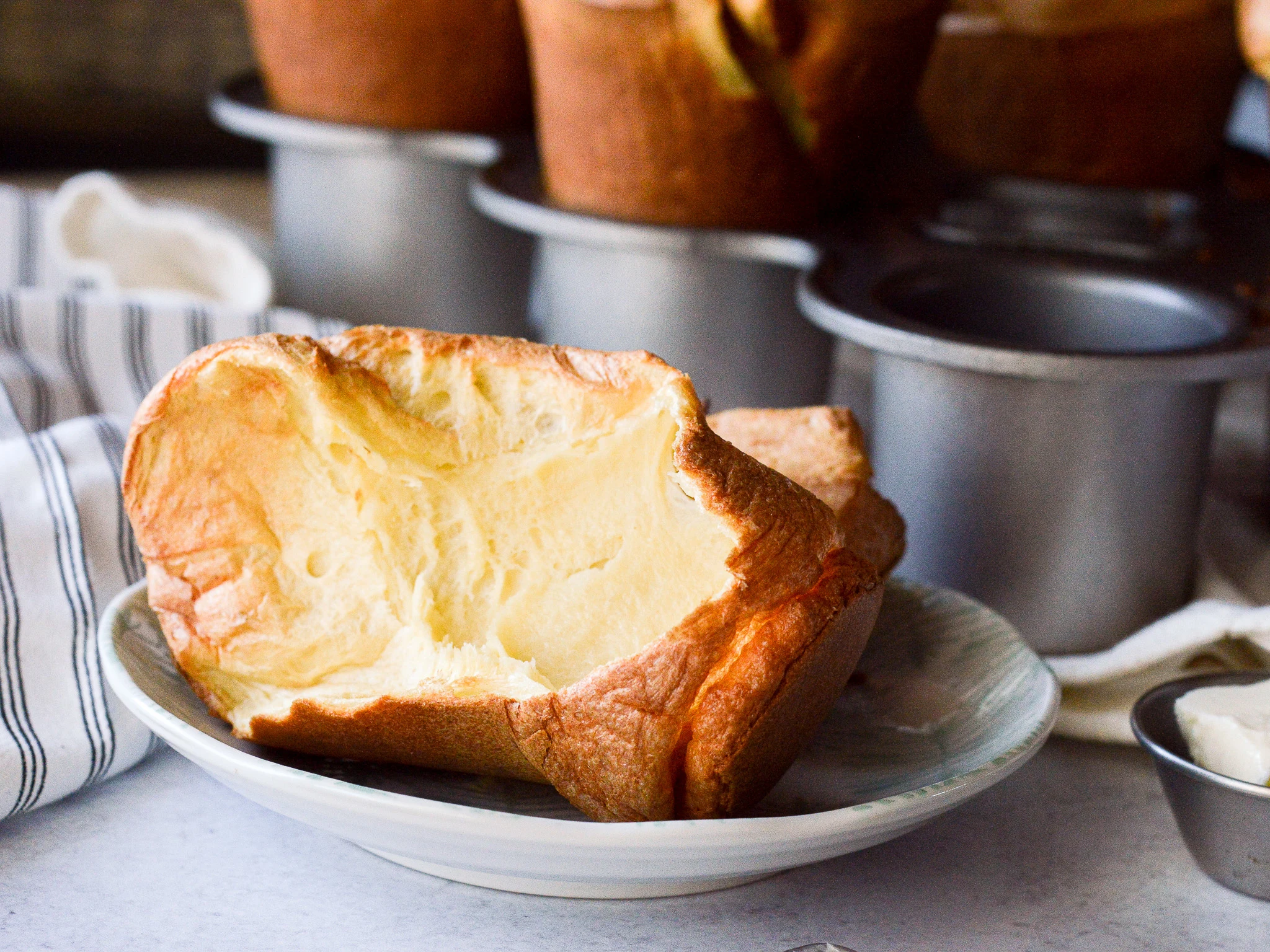 A split popover on a plate ready for butter and jam. 