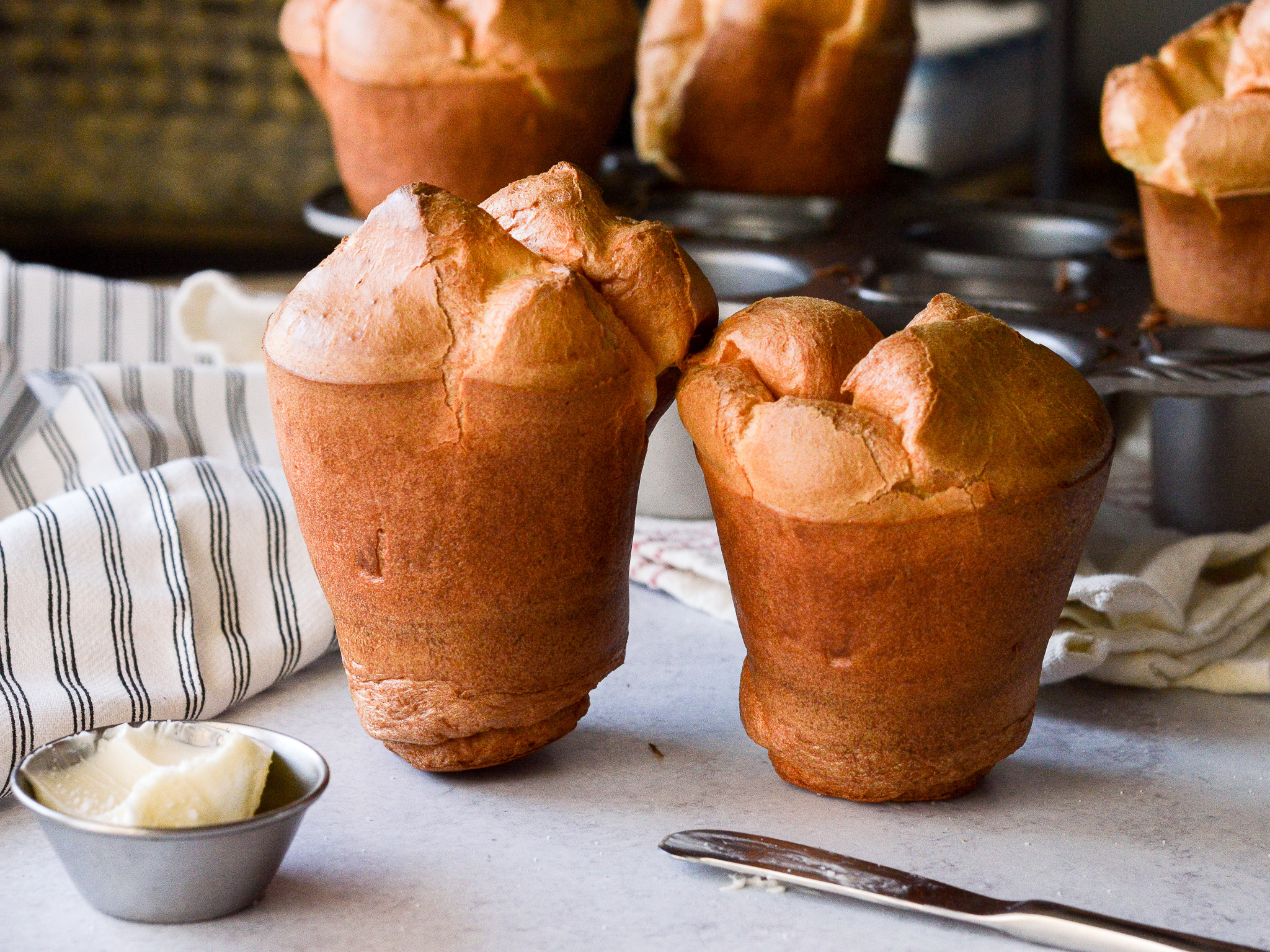 Two popovers side by side, one tall and completely risen, and one much shorter. 