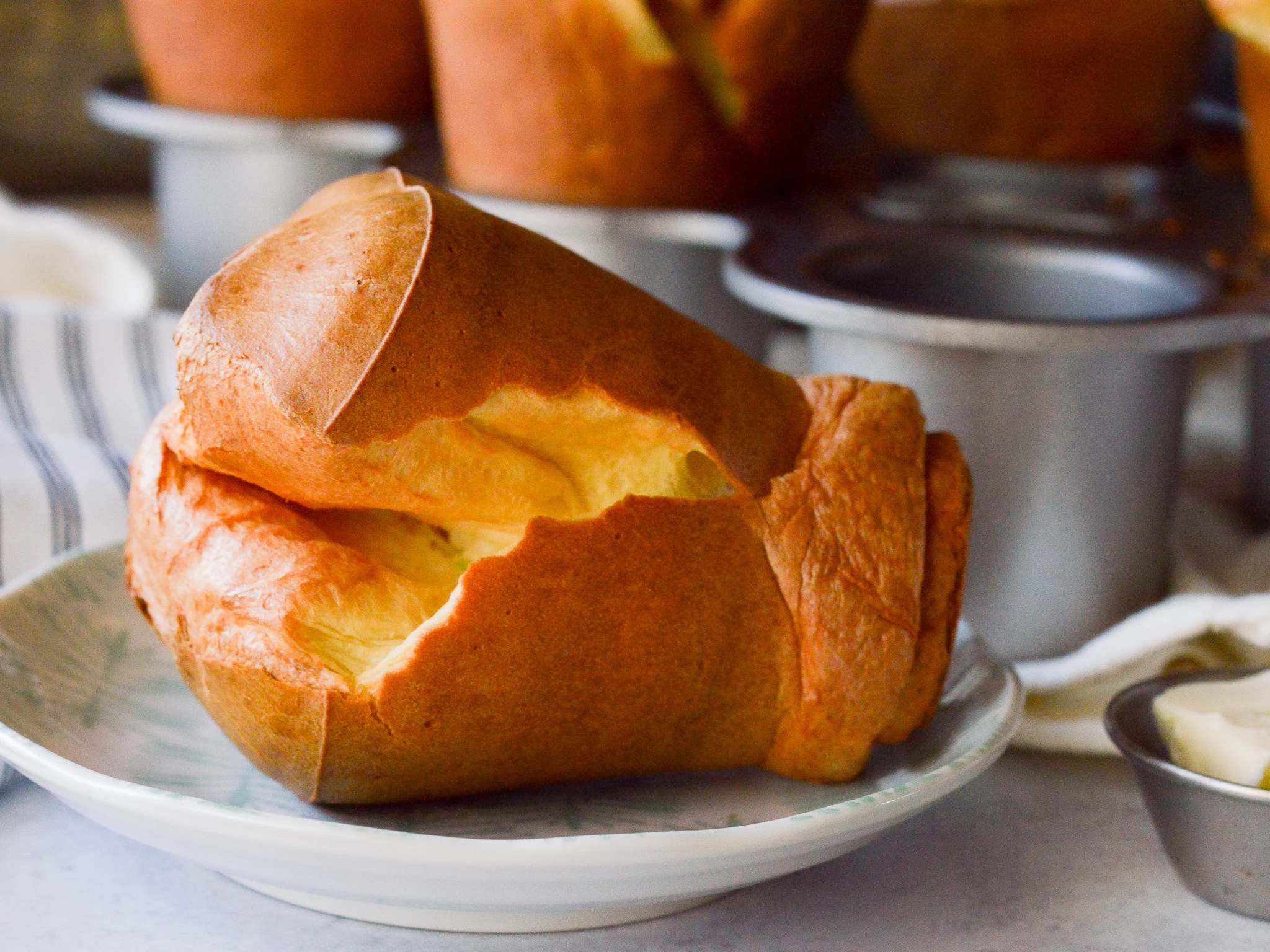 A fluffy popover made using a blender on a small plate ready to eat. 