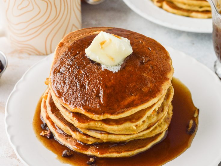 Sweet Potato Pancakes stacked on a plate with Cinnamon Syrup