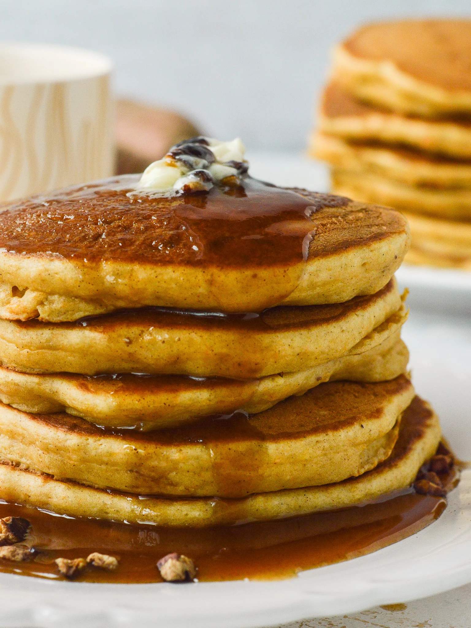 A stack of sweet potato pancakes very close up, doused with cinnamon syrup. 